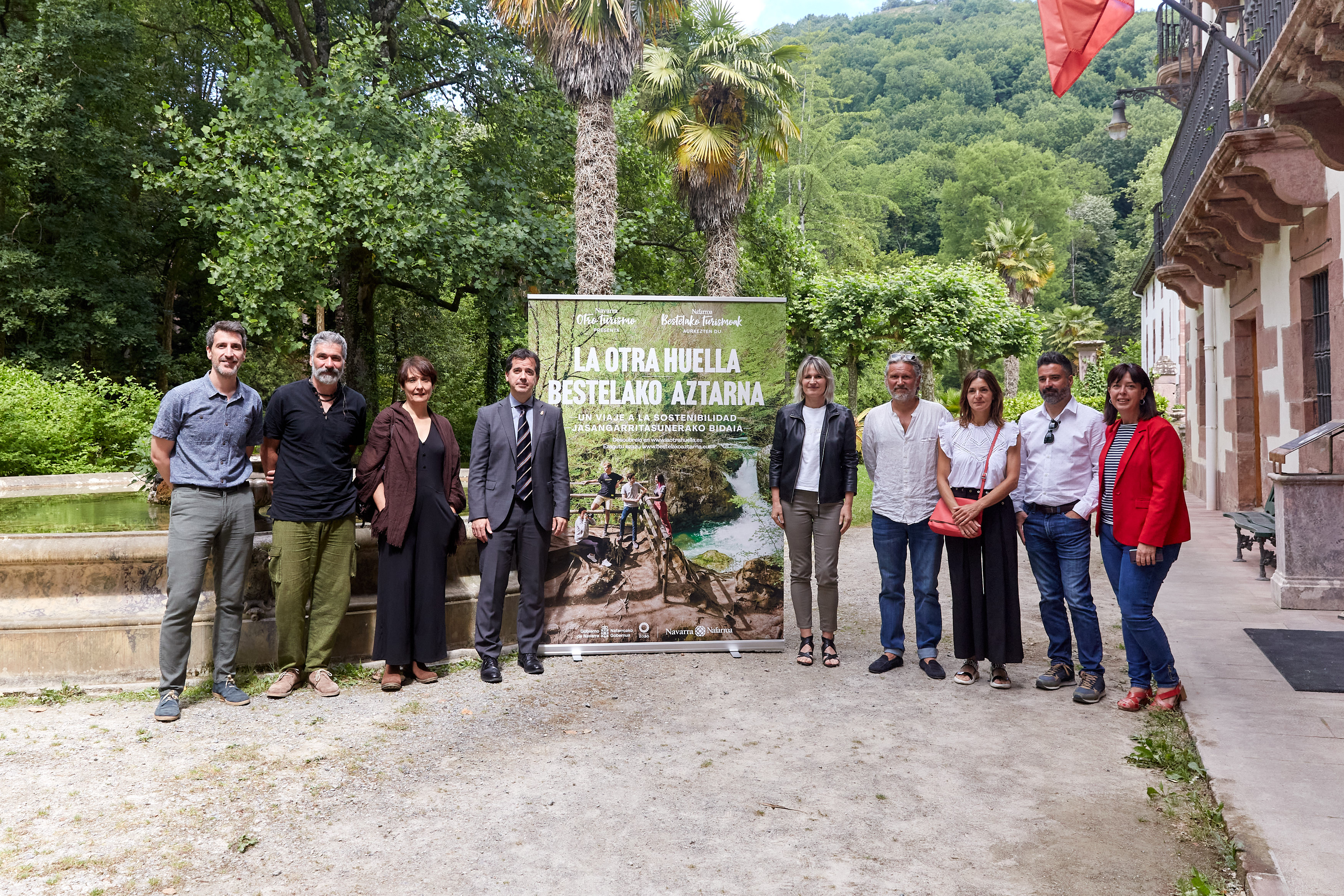 El consejero Irujo, la directora general Maitena Ezkutari, otras y otros representantes del Gobierno de Navarra, Nasertic, de la agencia de creatividad Hermosa y de Blua Producciones posan con el cartel que presenta el documental "La Otra Huella" de Turismo.