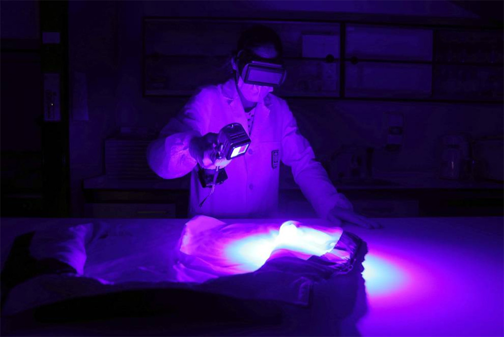 Selene Rol, especialista en ADN de la Policía Foral, examina una prenda con la luz forense.