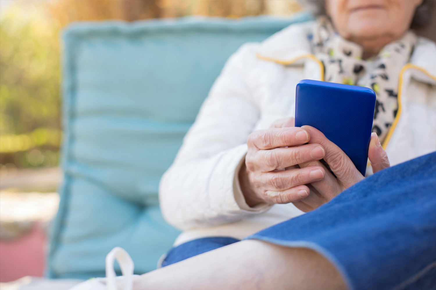 Mujer mayor mira la pantalla de un teléfono móvil azul oscuro